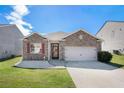 Charming single-story home with brick facade, attached garage, manicured lawn and vibrant red window shutters at 1907 Sea Oats Dr, Hampton, GA 30228