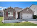 Charming single-story home with brick facade, attached garage, manicured lawn and vibrant red window shutters at 1907 Sea Oats Dr, Hampton, GA 30228