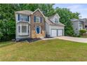 Charming two-story home features a brick and siding exterior with a two-car garage and well-manicured lawn at 4148 Kings Cswy, Ellenwood, GA 30294