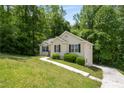 Well-maintained single-story home featuring a landscaped yard and a concrete walkway in a wooded area at 175 Hearth Way, Fairburn, GA 30213