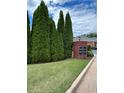 Landscaped entrance to The Courtyards at Towne Lake features a brick sign and mature evergreen trees at 401 Courtyard Ter, Woodstock, GA 30189