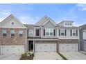 Stylish townhome boasts gray siding, brick accents, shutters, and two-car garage at 5365 Radford Loop, Fairburn, GA 30213