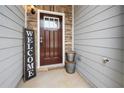 Front entrance with a dark wood door, a welcome sign, and exterior stone accents at 5365 Radford Loop, Fairburn, GA 30213