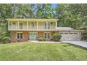 Two-story brick home featuring a light green exterior, white balcony, front lawn, and two-car garage at 1080 Northshore Dr, Roswell, GA 30076