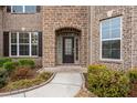 Close-up of the home's entrance with a stylish door, brick surround, and neat landscaping at 380 Parkside Meadow Dr, Marietta, GA 30064