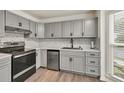 Modern kitchen features stainless steel appliances, gray cabinetry, marble backsplash, and hardwood floors at 3910 Meeting St, Duluth, GA 30096