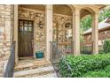 Inviting stone front porch with dark wood front door, columns, and black iron railing at 2672 Brickell Square, Atlanta, GA 30341