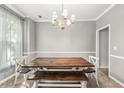 Formal dining room with a rustic wooden table set, neutral paint, and a traditional chandelier at 3220 Goldmist Dr, Buford, GA 30519
