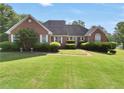Traditional brick home featuring manicured landscaping, pristine lawn, and lakeside property at 70 Lake Charles Xing, Covington, GA 30016
