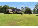 Classic brick home surrounded by a spacious lawn, mature trees, and serene lake views at 70 Lake Charles Xing, Covington, GA 30016