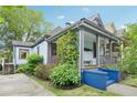 Charming two-story home featuring a covered porch, lush greenery, and blue painted stairs at 621 Mcgruder Ne St, Atlanta, GA 30312