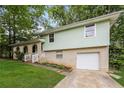 Split-level home features a brick facade, attached garage, and manicured lawn at 8857 Ashwood Dr, Riverdale, GA 30274