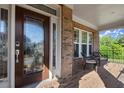 Inviting front porch with chairs, brick columns, and decorative front door with sidelight at 11240 Avery Cove Ct, Alpharetta, GA 30022