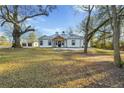 A farmhouse-style home with a large front yard, surrounded by beautiful mature trees and an outbuilding at 2711 Mcdonough Rd, Hampton, GA 30228