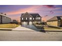 Charming two-story brick home features a two-car garage, landscaped yard, and sunset sky at 3621 Guinevere Trce, Douglasville, GA 30135