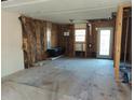 Living room under renovation, featuring exposed framing, a window, and an exterior door at 4195 Turner Dr, Cumming, GA 30040