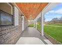 Inviting covered front porch with wood ceiling, brick accents, and stylish lighting at 897 Marie Sw Ln, Conyers, GA 30094