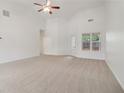 Spacious living room with neutral carpet, high ceilings, a ceiling fan, and ample natural light from the large window at 1065 City Park Dr, Mcdonough, GA 30252