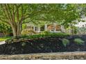 Landscaped front yard with a stone wall, mulch beds, mature trees and an archway leading to the home at 608 Sherwood Ne Rd, Atlanta, GA 30324