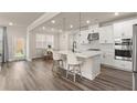 Open kitchen features an island with seating, stainless steel appliances, and wood flooring at 6100 Misty Hill Ln, Buford, GA 30518