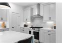 Stylish kitchen featuring stone backsplash, stainless hood, and shaker cabinets at 3319 Stillwood Ln, Hapeville, GA 30354
