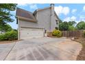View of the garage and driveway with well-kept landscaping on a sunny day at 944 Hidden Falls Se Ln, Smyrna, GA 30082
