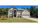 Charming two-story home featuring a gray brick facade, well-manicured lawn, and an attached two-car garage at 5010 Lynnonhall Ct, Stonecrest, GA 30038
