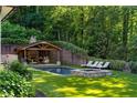 Backyard pool featuring a spa, covered pavilion with a fireplace, and lush landscaping for privacy at 5360 Lake Forrest Dr, Atlanta, GA 30342