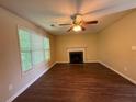 Living room featuring hardwood floors, a ceiling fan, a fireplace, and natural light from a large window at 4649 Camelot Dr, Douglasville, GA 30135
