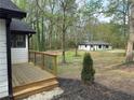 Exterior view from the deck shows a large lot with mature trees and the renovated white and black house at 12836 Cumming Hwy, Canton, GA 30115