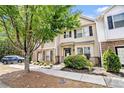 Inviting townhome featuring a manicured lawn, mature tree, and a paved walkway leading to the entrance at 7244 Rockhouse Rd, Austell, GA 30168