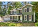 Well-maintained two-story home showcasing a welcoming front porch, classic shutters, and lush landscaping at 1027 Spring Mill Sw Dr, Lilburn, GA 30047