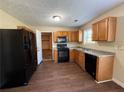 Functional kitchen featuring classic oak cabinets, black appliances, and vinyl floors at 3836 Wexford Dr, Douglasville, GA 30134