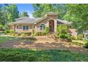 Beautiful brick home featuring an arched entry, well-maintained landscaping, and lush green trees at 5816 Chamblee Dunwoody Rd, Atlanta, GA 30338