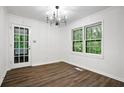 Bright dining room with modern chandelier and large windows offering peaceful view to a lush and verdant forest at 6032 Lakeshore Se Dr, Mableton, GA 30126