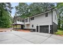 View of the home's rear elevation, showcasing the large deck, garage, and expansive concrete driveway at 6032 Lakeshore Se Dr, Mableton, GA 30126