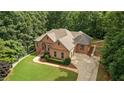 An elevated view of brick home highlighting the driveway, lawn, and mature surrounding trees at 7940 Gable Dr, Douglasville, GA 30135