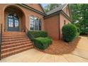 Close-up view of a charming brick home showcasing the arched entrance and manicured landscaping at 7940 Gable Dr, Douglasville, GA 30135