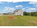 View of a two-story home featuring neutral siding, black shutters, a two-car garage, and a large grassy lawn at 294 Ralph Still Rd, Dacula, GA 30019