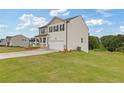 View of a two-story home featuring neutral siding, black shutters, a two-car garage, and a large grassy lawn at 294 Ralph Still Rd, Dacula, GA 30019