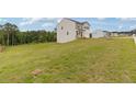 View of a two-story home featuring neutral siding, black shutters, a two-car garage, and a large grassy lawn at 294 Ralph Still Rd, Dacula, GA 30019