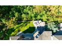 Aerial view of a backyard featuring a green lawn, stone walls, a patio with an outdoor seating, and mature trees at 9675 Almaviva Dr, Alpharetta, GA 30022
