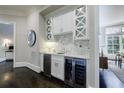 A stylish bar area with white cabinets, marble backsplash, wine cooler, and a view into an adjacent dining room at 9675 Almaviva Dr, Alpharetta, GA 30022