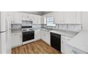 Well-lit kitchen with white cabinetry, modern appliances, and laminate floors at 9511 Rollinghills Dr, Jonesboro, GA 30238