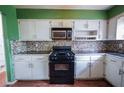 A view of the kitchen with black appliances, mosaic backsplash, and white cabinets at 1443 Snapfinger Rd, Decatur, GA 30032
