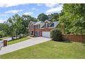 A two-story brick home with a long driveway, garage, and lush green lawn at 2350 Twelvestones Dr, Roswell, GA 30076