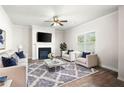 Living room with a fireplace, ceiling fan, stylish rug, and large window allowing for natural light at 33 N Village Cir, Rydal, GA 30171