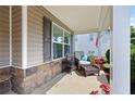 Relaxing side porch with a comfortable chair, ottoman, and a small table with red flowers at 102 Autumn Brooke Trl, Dallas, GA 30157