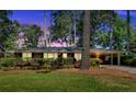 Charming brick home with lush landscaping and a covered carport, beautifully captured at twilight at 561 Sybil Se Ln, Marietta, GA 30067