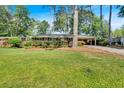 Charming brick home with lush landscaping and a covered carport nestled among mature trees on a well-manicured lawn at 561 Sybil Se Ln, Marietta, GA 30067